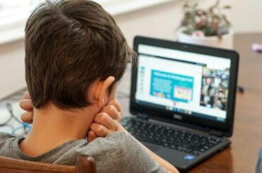 boy in gray shirt using black laptop computer