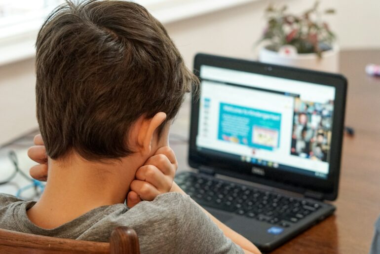 boy in gray shirt using black laptop computer